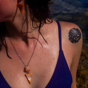Candy, juego de aretes con cadenita y dije elaborado con conchas naturales y tonos naranja inspirados en dulzura veraniega.